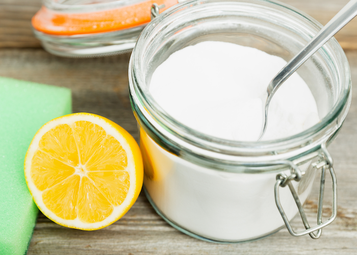 Cut lemon sits next to jar of sugar and sponge on counter