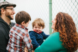 Image of white father and mother with two boys smiling and looking at one another