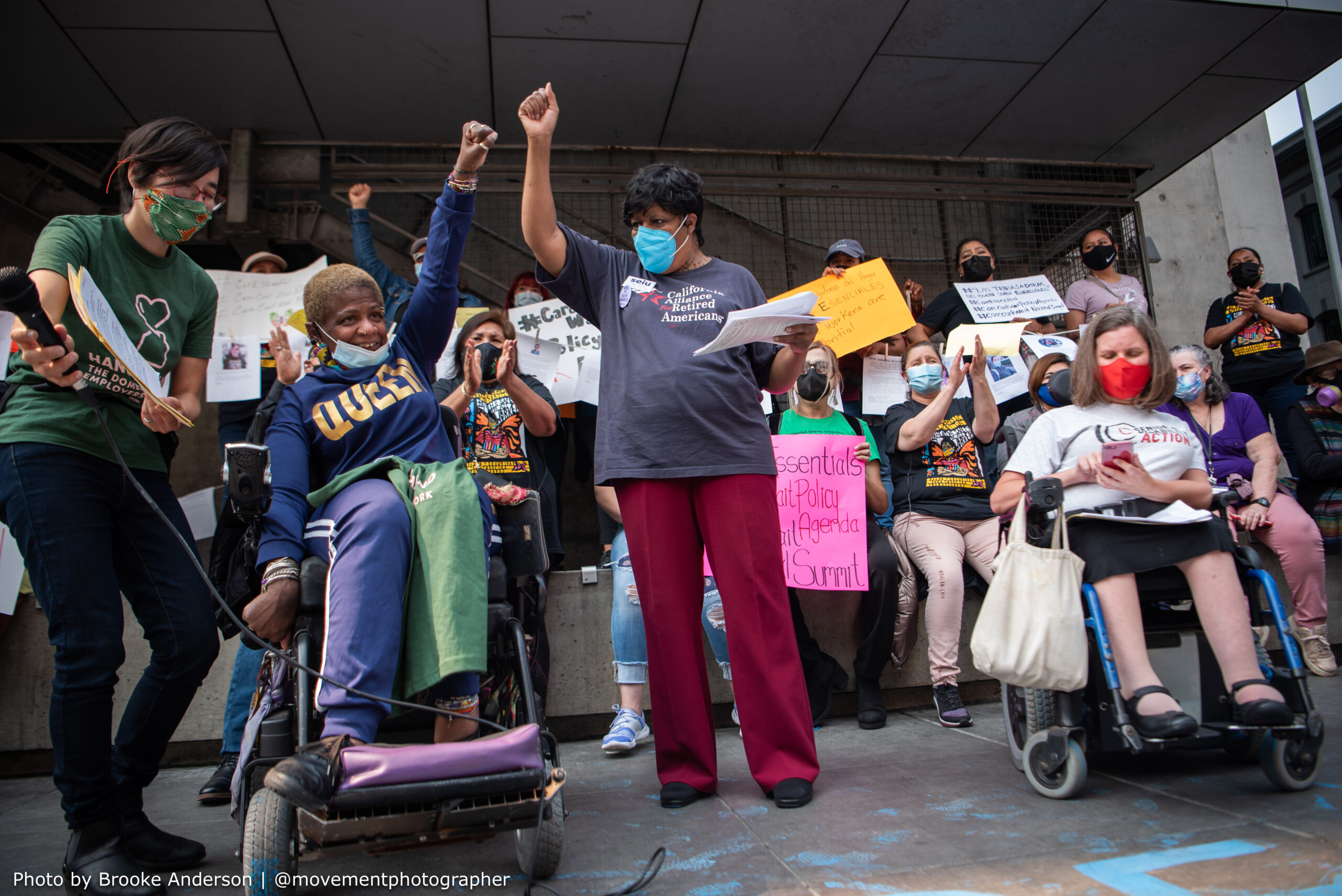 Group standing and sitting in wheelchairs with fists raised.