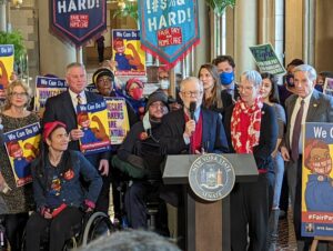 Group of legislators and supporters holding signs for Fair Pay for Home Care