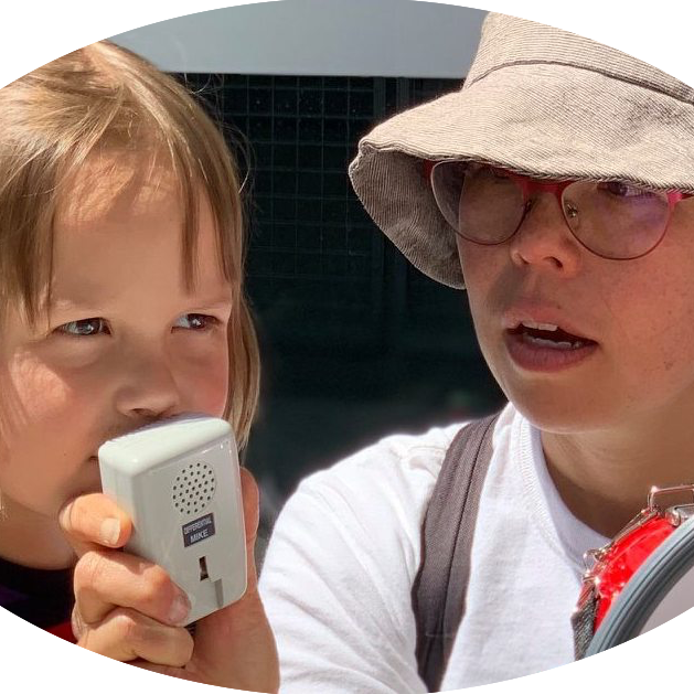 image of woman wearing a hat lifting microphone for a child to speak