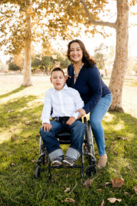 photo of women standing outside next to her son seated in wheelchair.