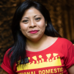 Photo of woman with long black hair, wearing read national domestic workers alliance t-shirt. 