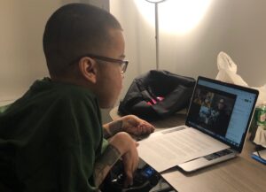 latino man in wheelchair sitting in front of a laptop