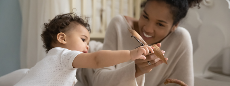 A lady smiling while playing with a baby. 