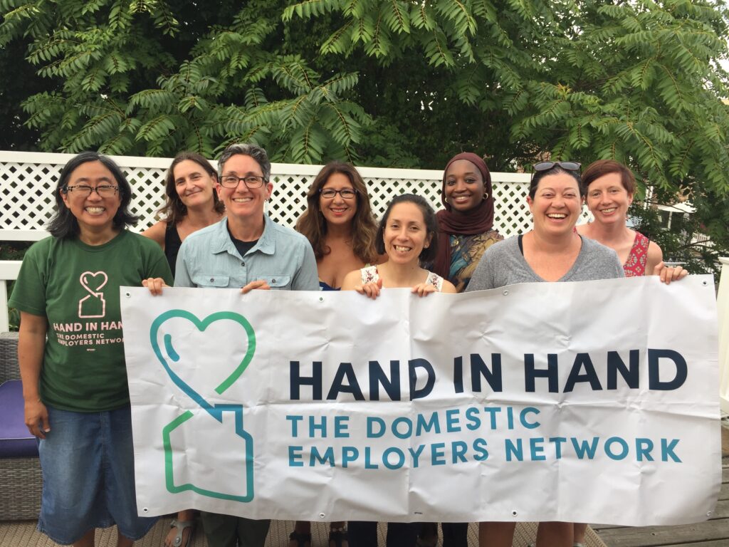 Hand in hand staff members holding Hand in Hand's banner outside.