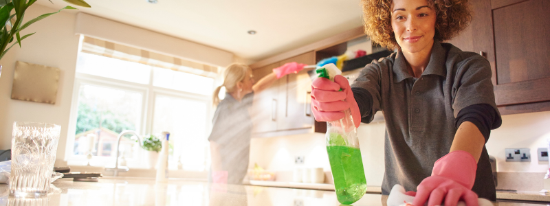 Two house cleaners cleaning a kitchen .