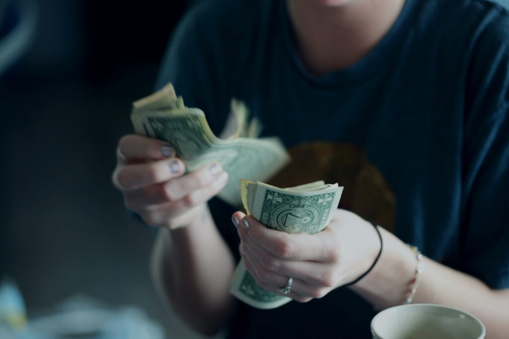 A woman wearing a blue shirt counts dollar bills.