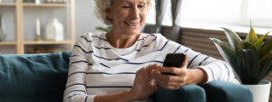 An elderly white woman wearing a horizontally striped shirt, while using a phone.