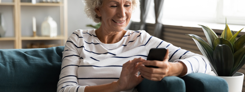 An elderly white woman wearing a horizontally striped shirt, while using a phone. 