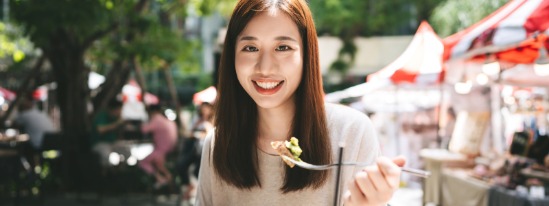 An asian woman with medium-length hair holding a spoon with food on it. 