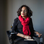 Ligia Andrade Zúñiga sitting in a wheelchair wearing a black dress and red scarf.