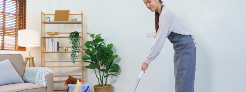 A white woman mopping the floor with a swifter in hand.