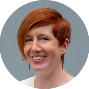 A headshot of a white woman with ginger hair, smiling.