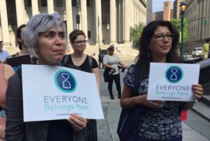 Two Hand in Hand Members hold signs reading "Everyone Belongs Here"