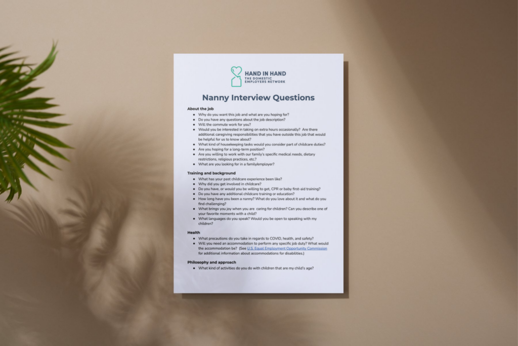 A sheet of paper with interview questions printed on it sits on a tan table alongside a plant.