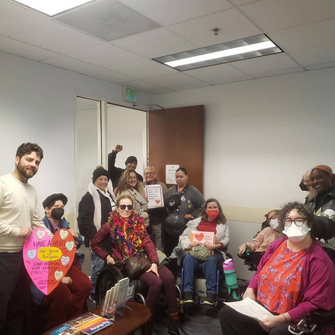 A group of people sit and stand in an office holding valentines