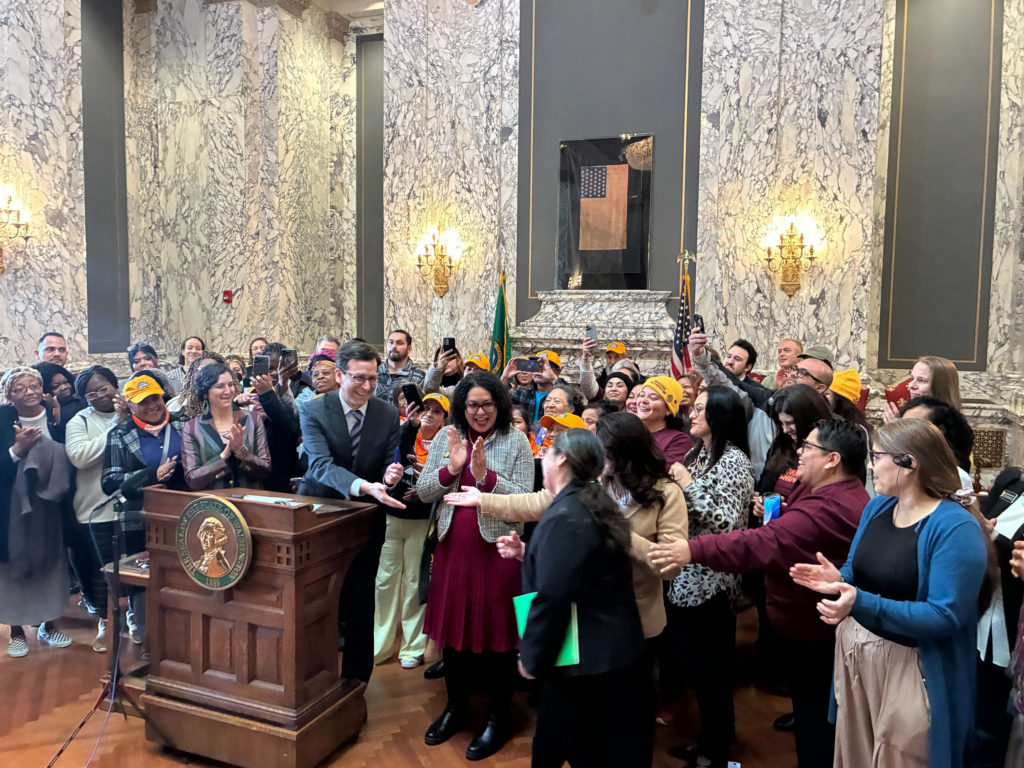 A group of people celebrate with the Washington governor after the passage of the Domestic Worker Bill of Rights